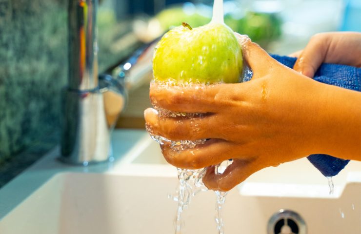 Una mela sciacquata sotto acqua corrente