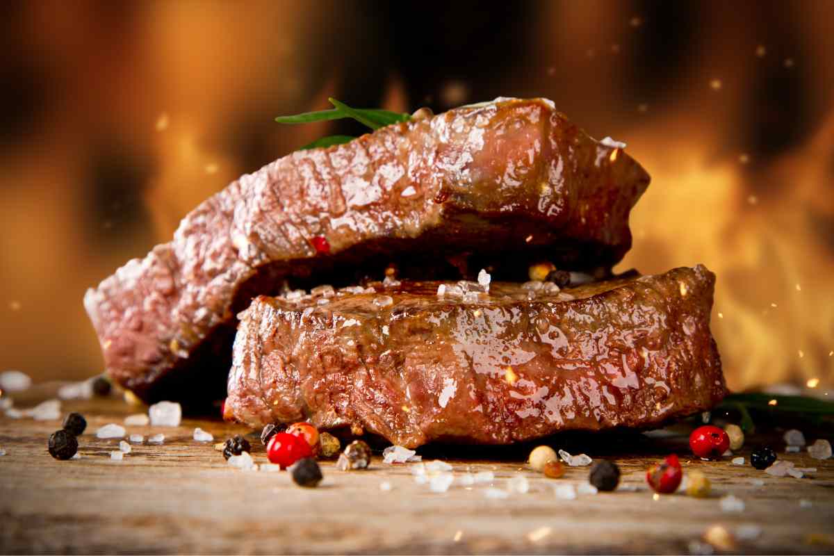 tagliata di manzo al rosmarino su un tavolo con del fuoco sullo sfondo