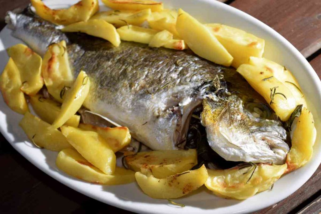 Orata al forno in un vassoio con contorno di patate