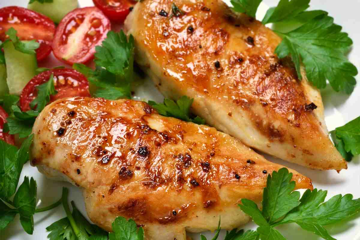 primo piano di due petti di pollo al forno guarniti con prezzemolo e contornati da pomodorini