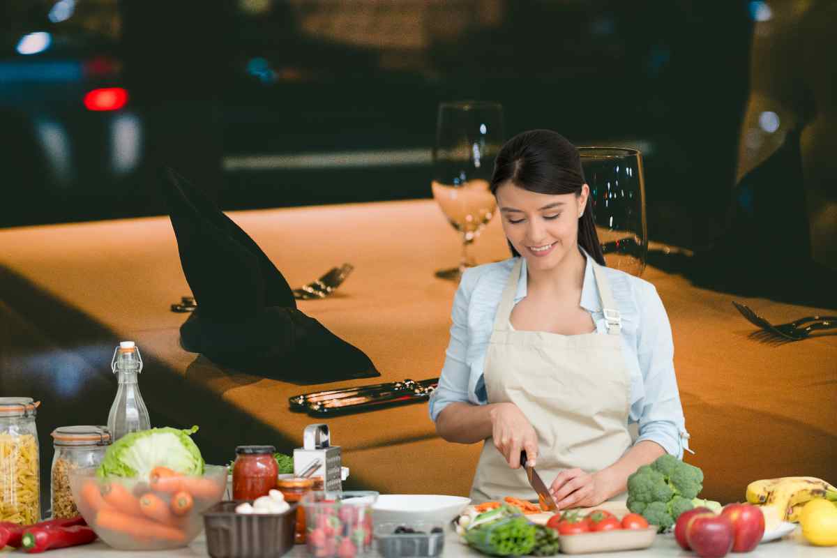 Tavola apparecchiata di sera ed una donna che cucina