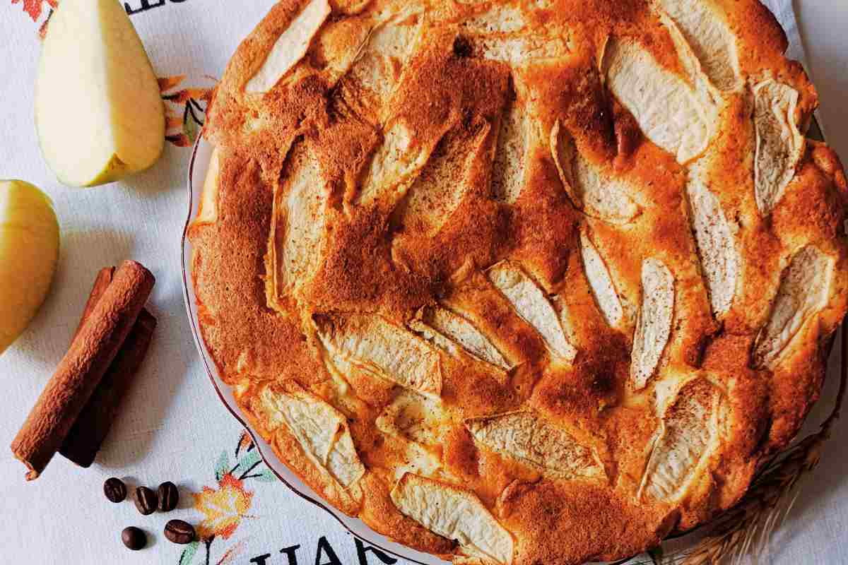 Torta di mele con uno spicchio di mela e stecche di cannella vicino vista dall'alto