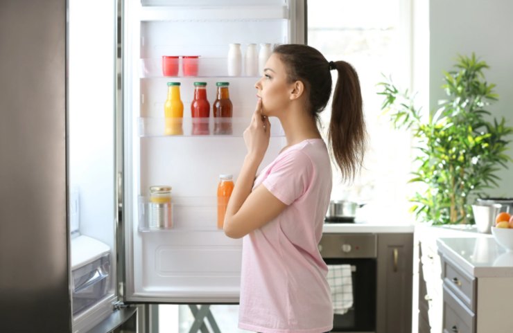 donna in piedi davanti al frigo aperto