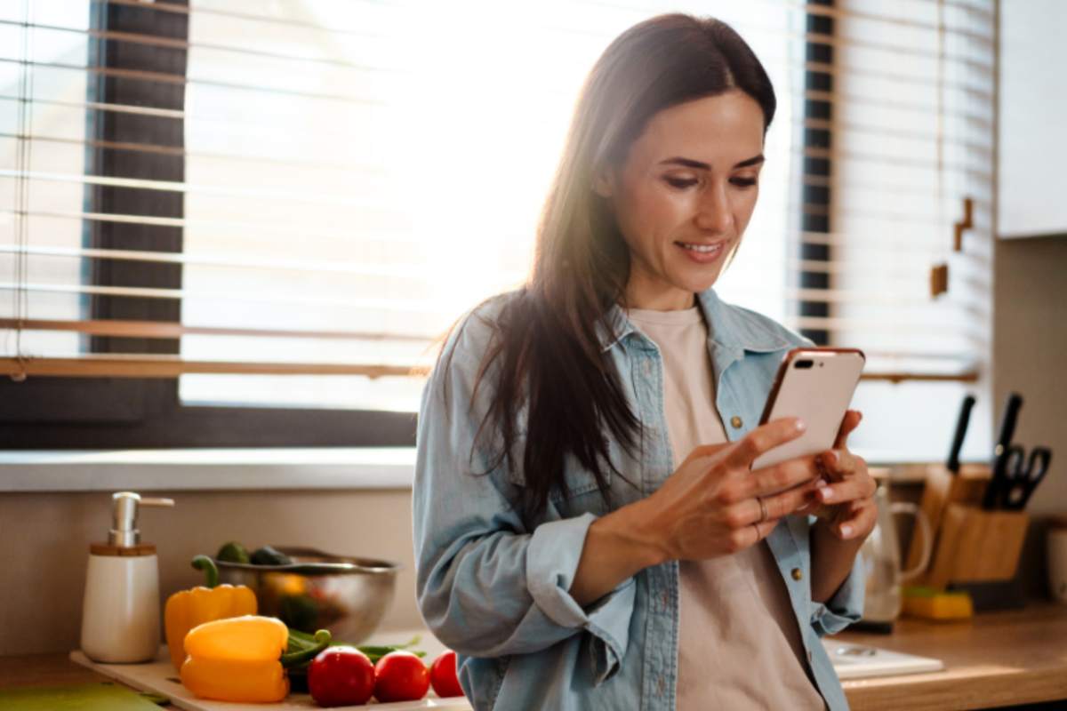 donna in cucina con il cellulare in mano
