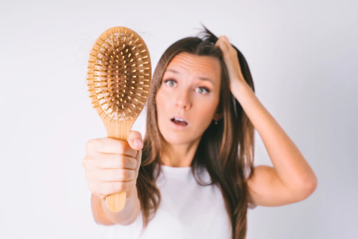 donna con in mano la spazzola piena di capelli