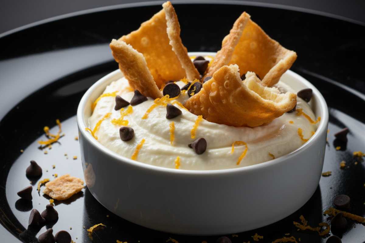 una ciotola con crema di ricotta, gocce di cioccolato e gusci di cannolo rotti