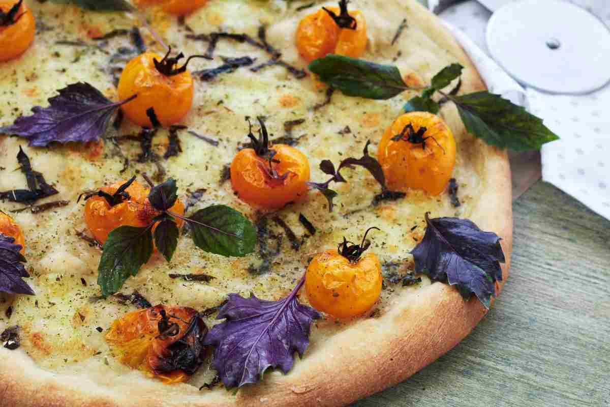 una pizza con formaggio e pomodorini gialli