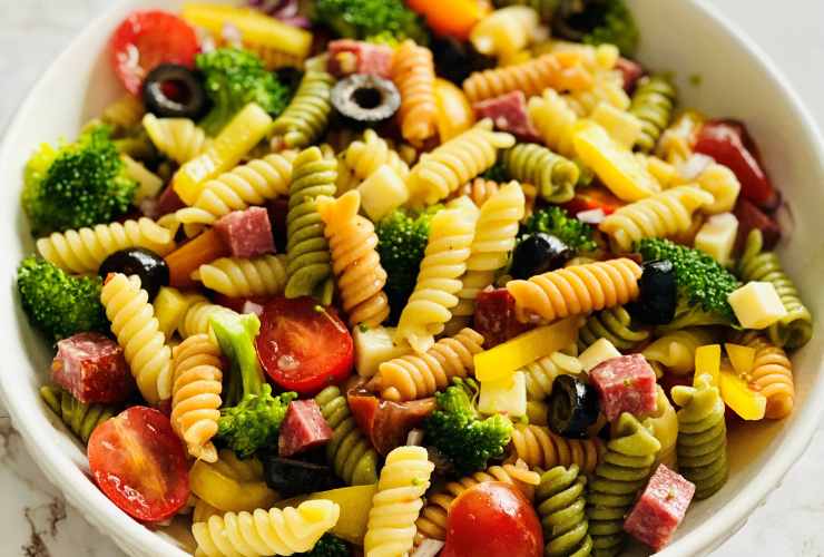 piatto di insalata di pasta con olive, pomodoro, broccoli e salame