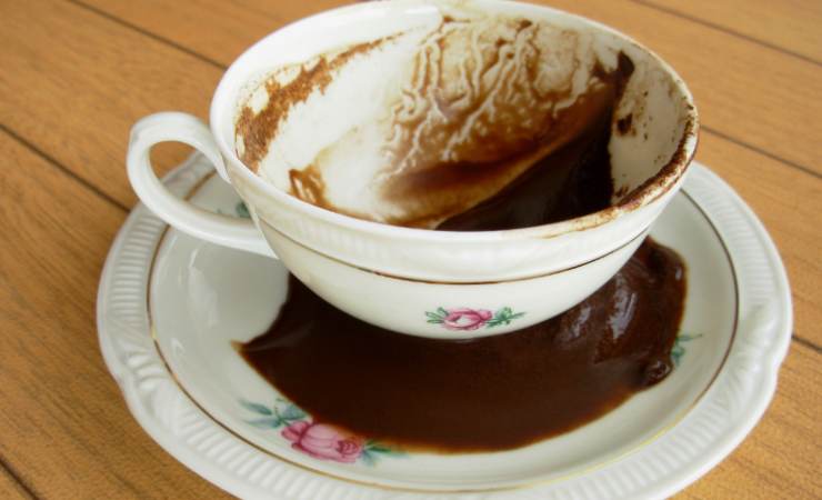 tazzina e caffè rovesciato nel piattino