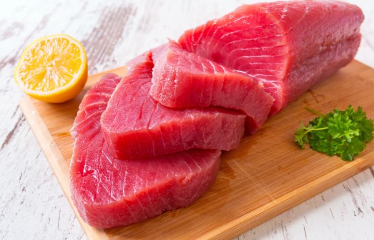 tranci di tonno crudo su un tagliere con accanto mezzo limone