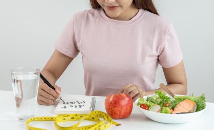 donna che scrive, insalata e mela