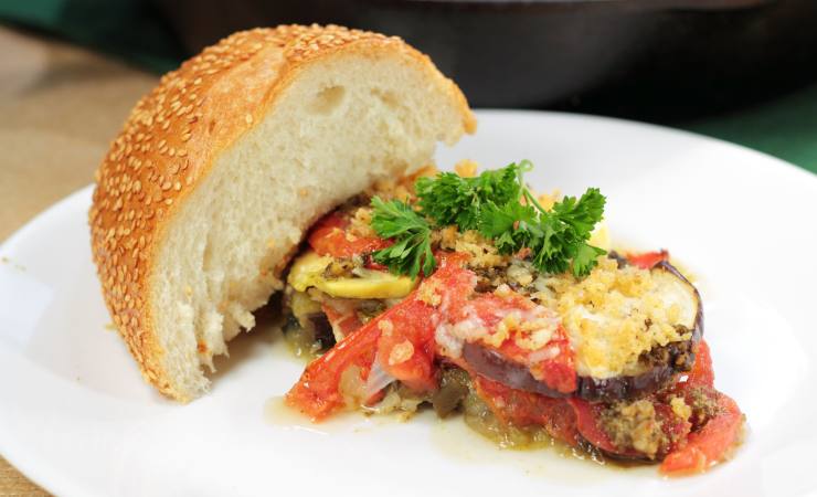 pomodori e melanzane gratinate su piatto con pezzo di pane