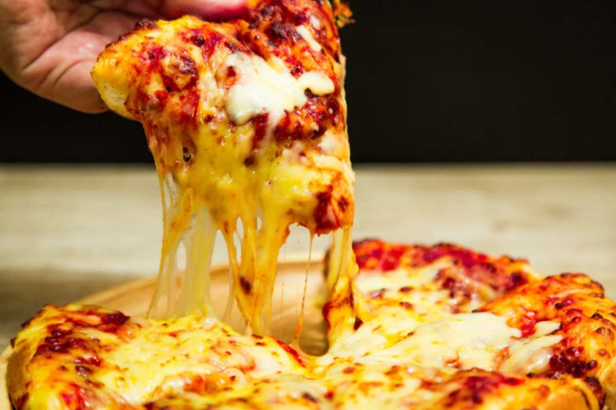 uomo che prende una fetta di pizza con pomodoro e formaggio filante