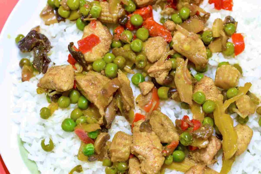 Piatto con bocconcini di pollo e piselli con riso in bianco visto dall'alto