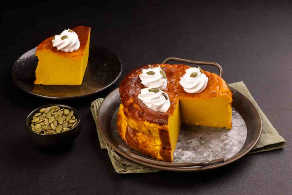 Cheesecake di zucca al forno in un vassoio con una fetta posta in un piattino