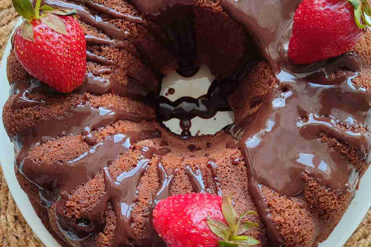 un ciambellone al cacao visto dall'alto, guarnito con salsa al cioccolato e fragole