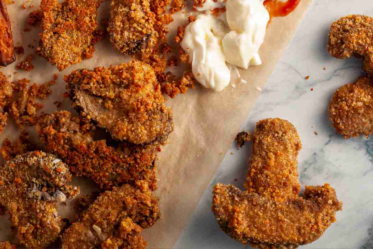 Cotolette di funghi con uno spruzzo di maionese su carta forno
