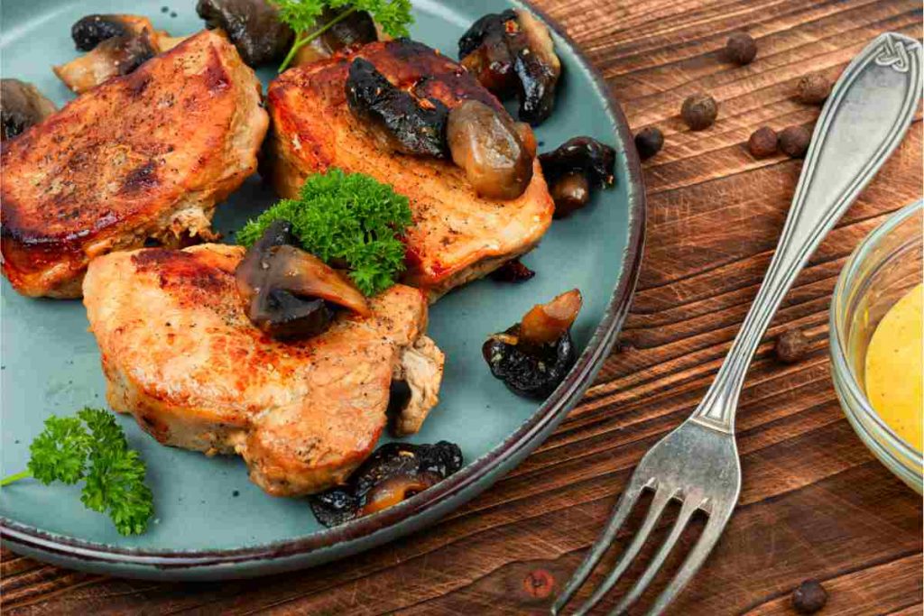 fette di filetto di maiale ai funghi porcini in un piatto blu