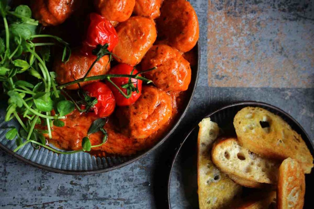 piatto di gnocchi e ricotta visto dall'alto vicino a un piattino con fette di pane tostato