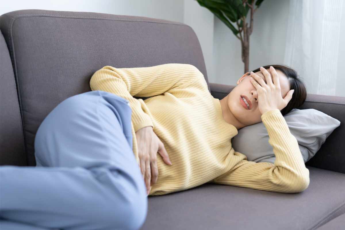 Una donna stesa sul divano col mal di pancia