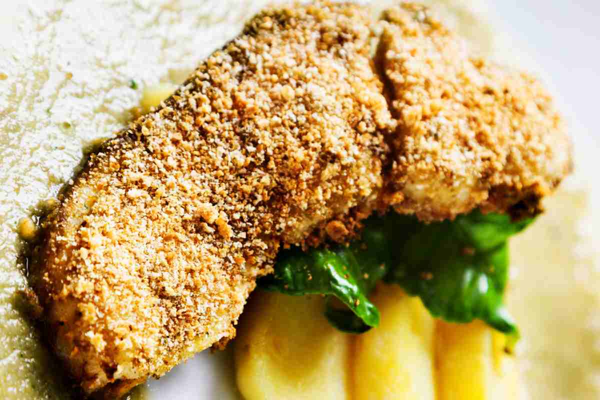 una fetta di pesce spada impanato su spicchi di patate