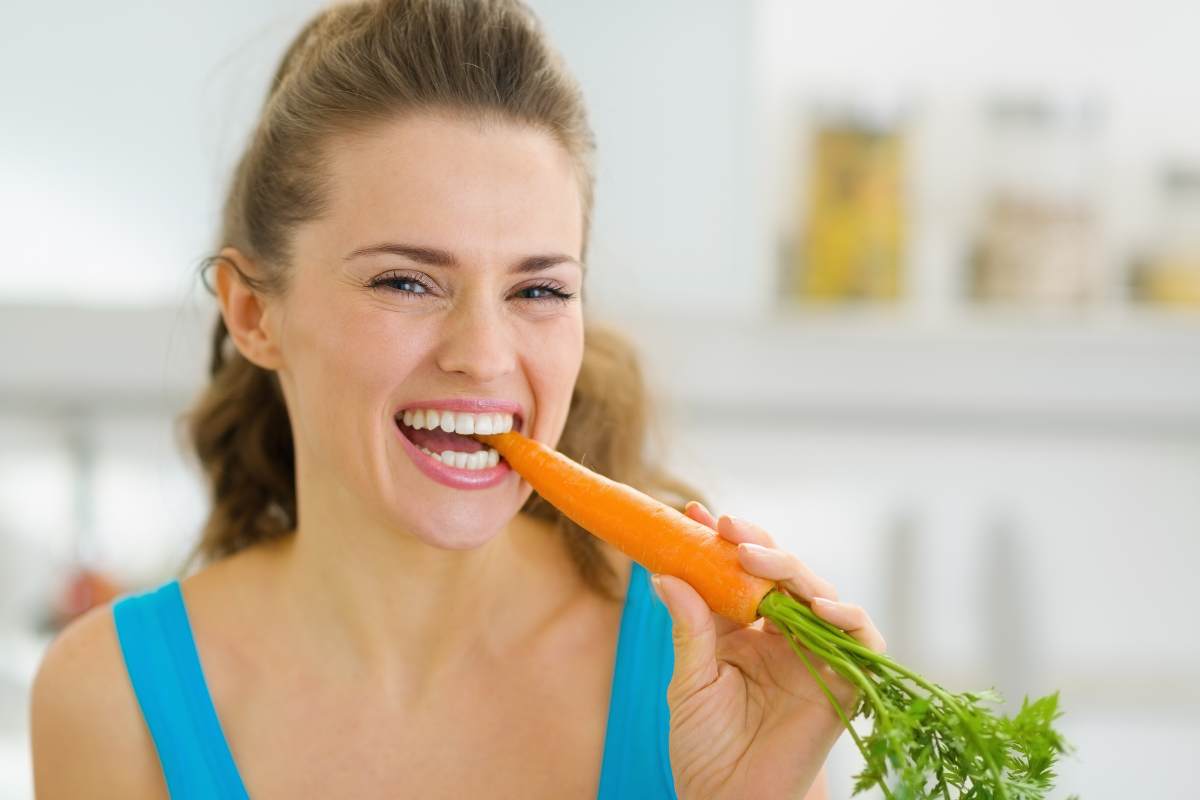 Donna sorridente che addenta una carota