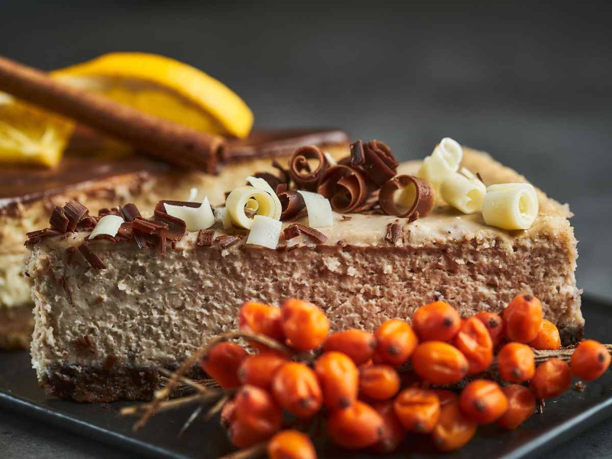 fetta di cheesecake con frutta accanto e cioccolato