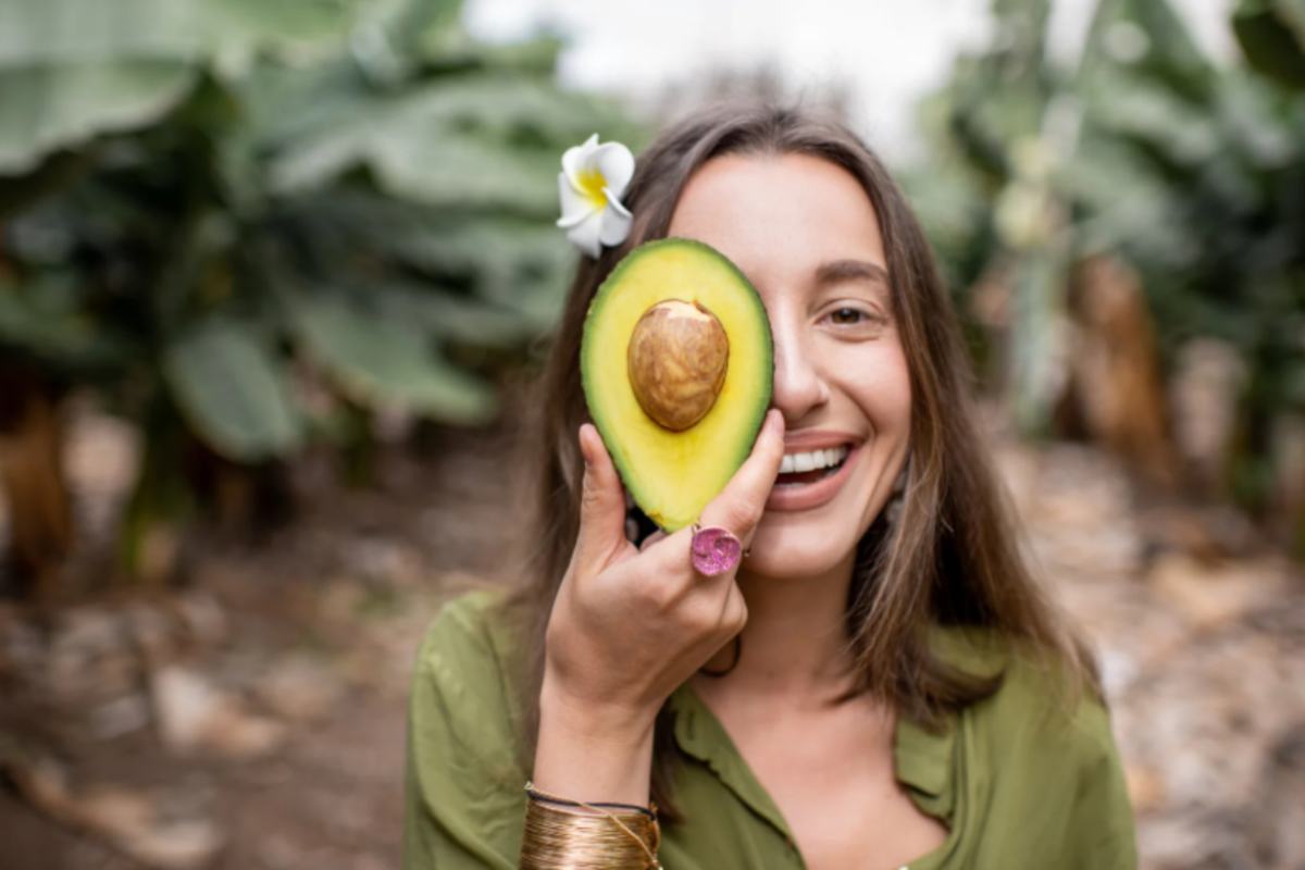 donna che sorride con mezzo avocado davanti ad un occhio