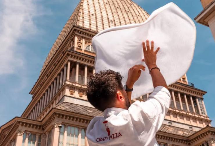 un pizzaiolo del crazy pizza che impasta la pizza sotto la Mole Antonelliana a Torino