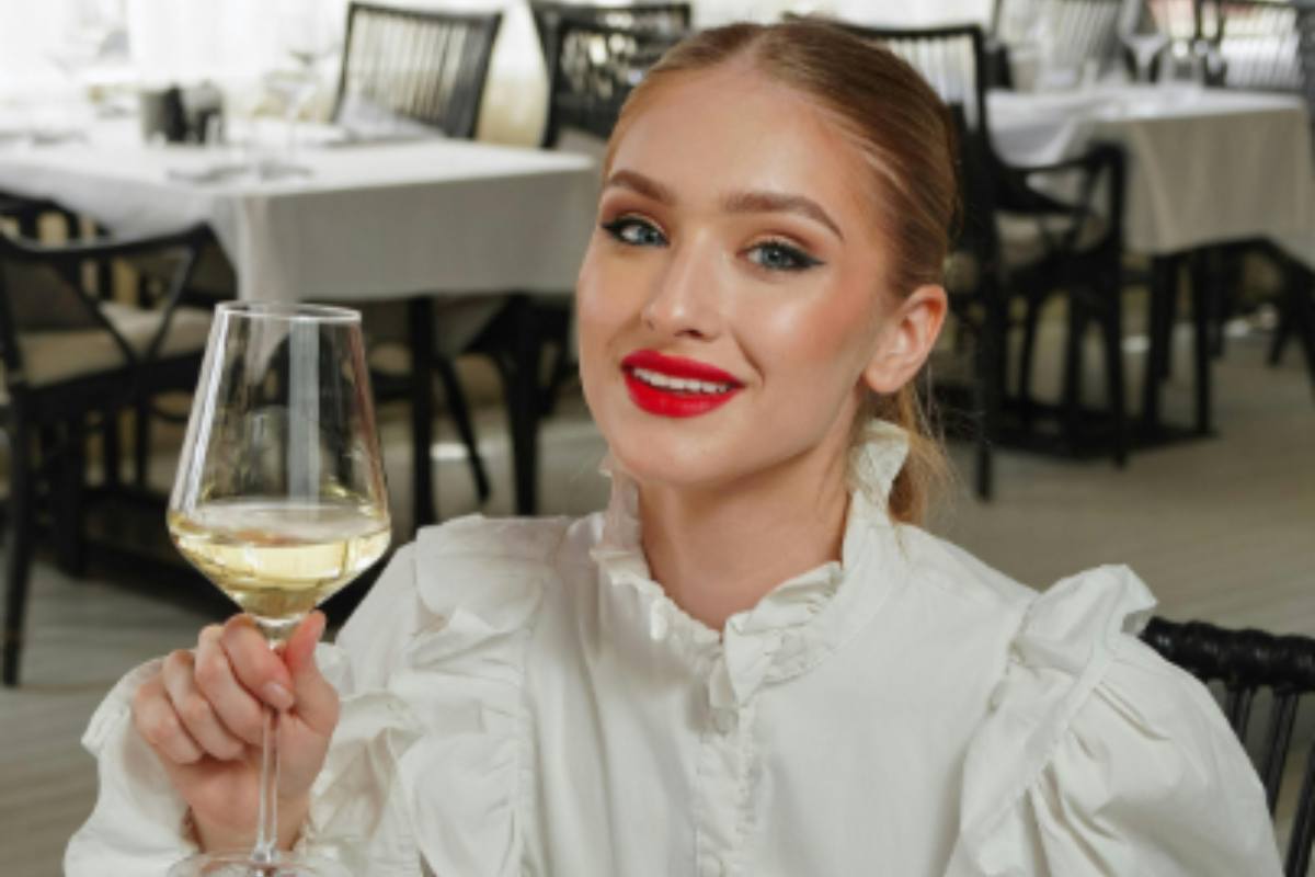 donna al ristorante con in mano un calice di vino bianco
