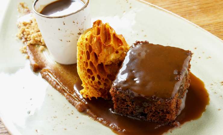 sticky toffee pudding su piatto con tazza di caffè