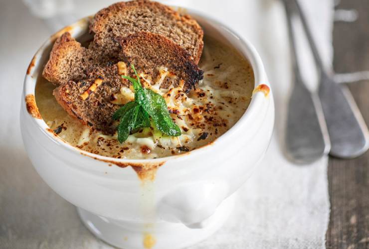 ciotola di zuppa di cipolle con pane tostato e posate