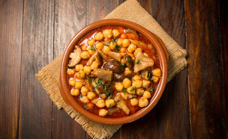 pentola in terracotta con zuppa di ceci e funghi 