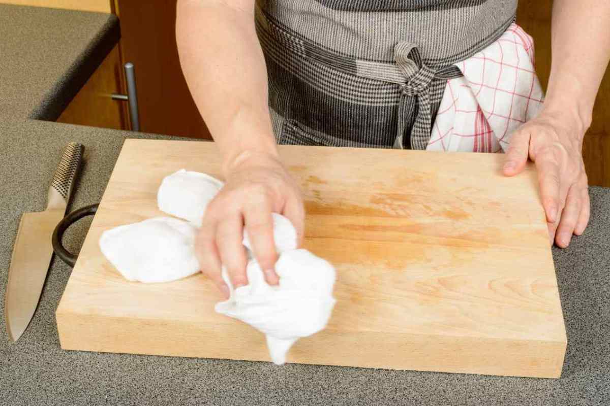 persona che pulisce un tagliere in legno