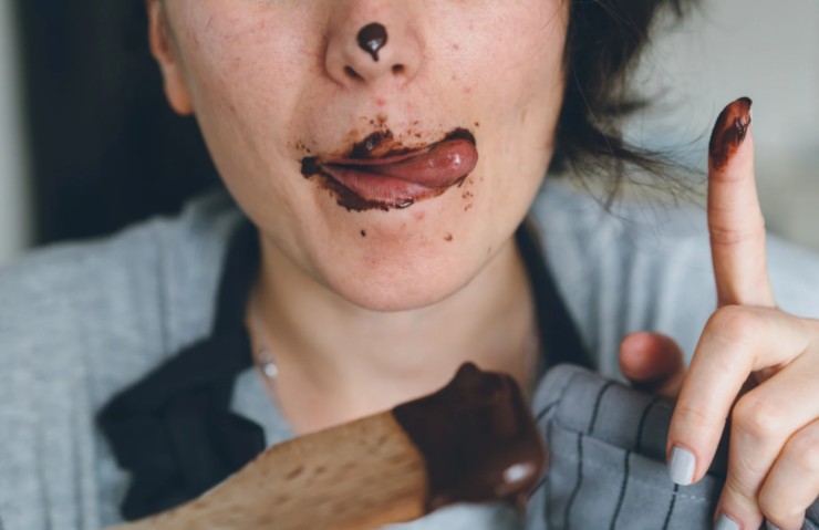 donna con un dito e la bocca sporchi di cioccolato