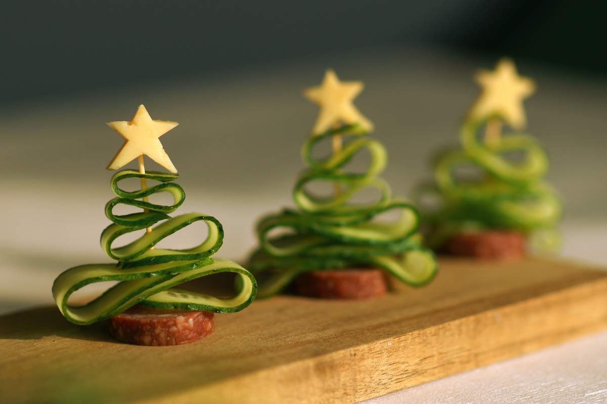 Alberelli di cetriolo e salame su un tagliere di legno