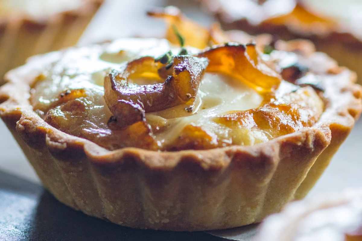 primo piano su una crostatina salata farcita con cipolle e pancetta