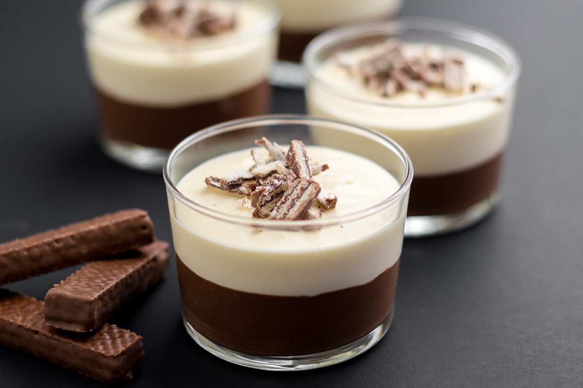 4 mousse ai due cioccolati in coppa vicino a dei wafer al cioccolato