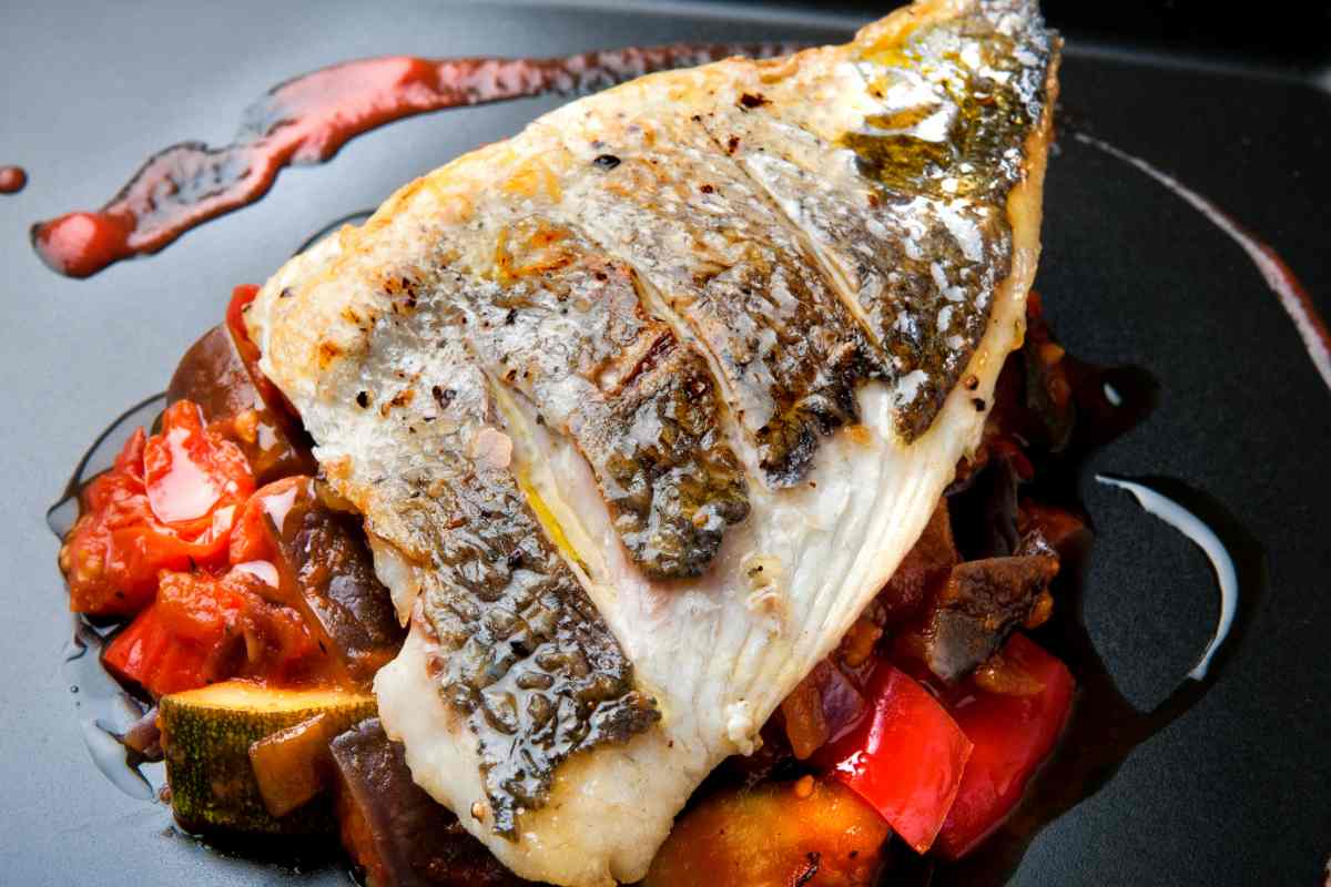 un filetto di orata al forno su un contorno di verdure grigliate