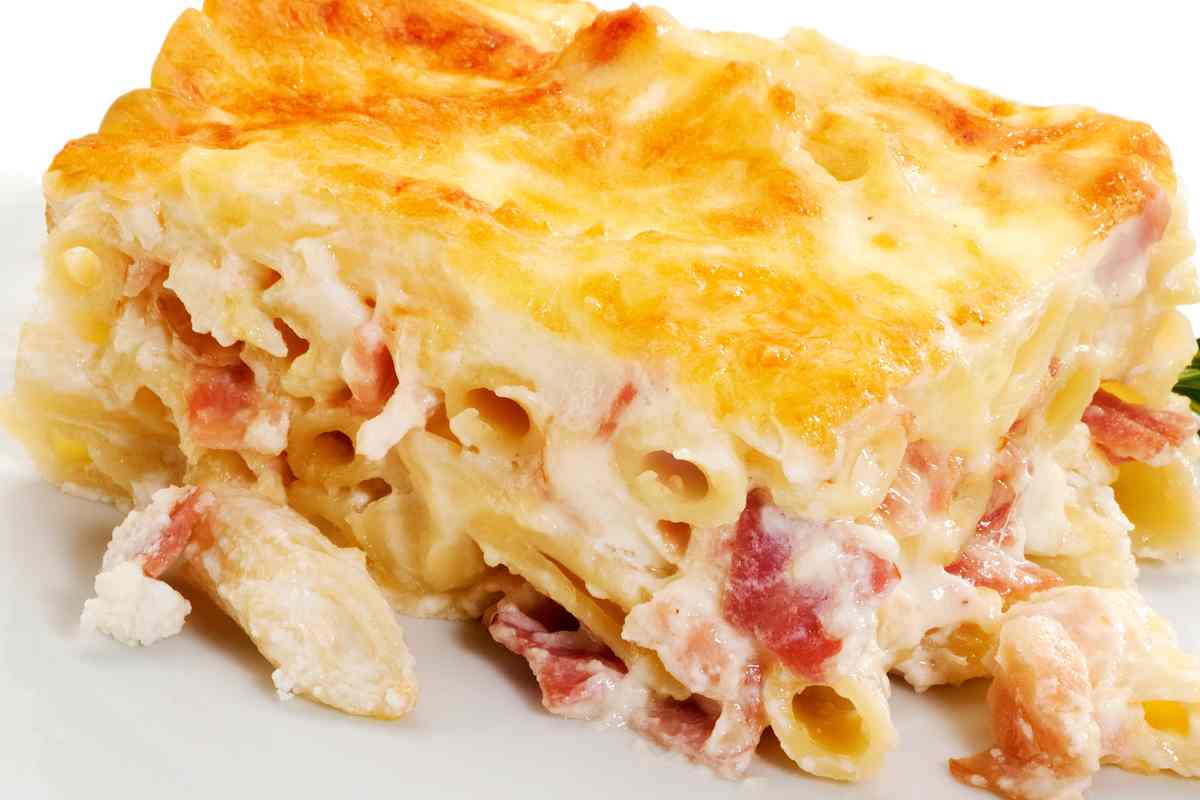 una fetta di pasta al forno gratinata con cubetti di prosciutto cotto
