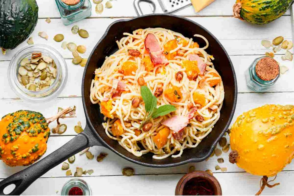 una padella con pasta condita con zucca e bacon vista dall'alto