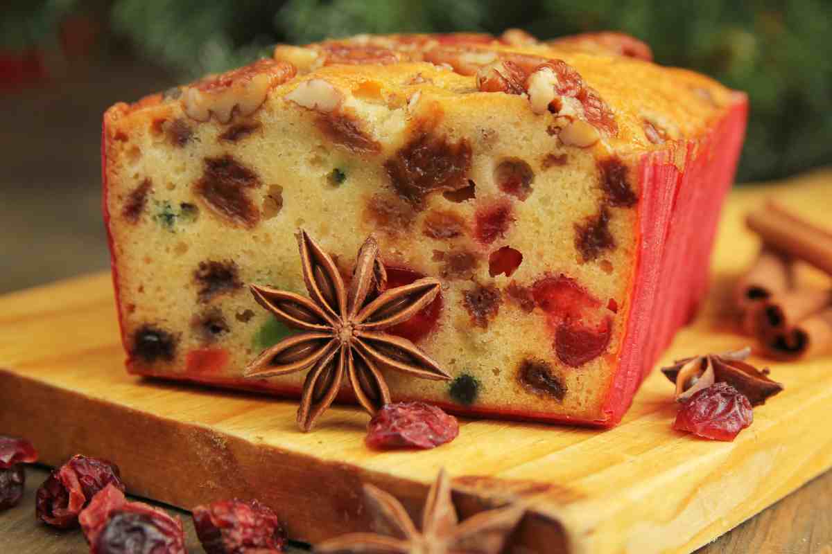Plum cake di Natale con frutta candita su un tagliere di legno