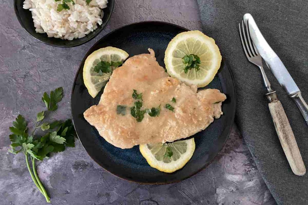 Scaloppina con salsa di limone in un piatto vista dall'alto