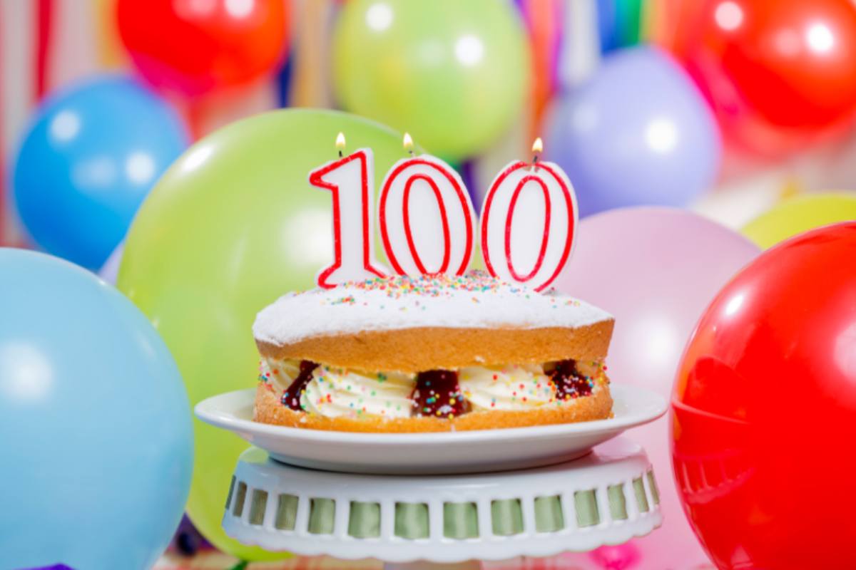 palloncini colorati e torta con sopra il numero 100