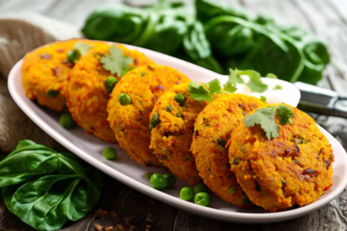 burger vegetali su un piatto e intorno dei piselli e degli spinaci