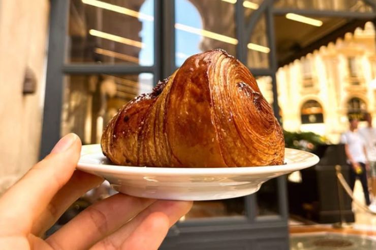 persona che tiene in mano un piattino con sopra una brioche al cioccolato di carlo cracco