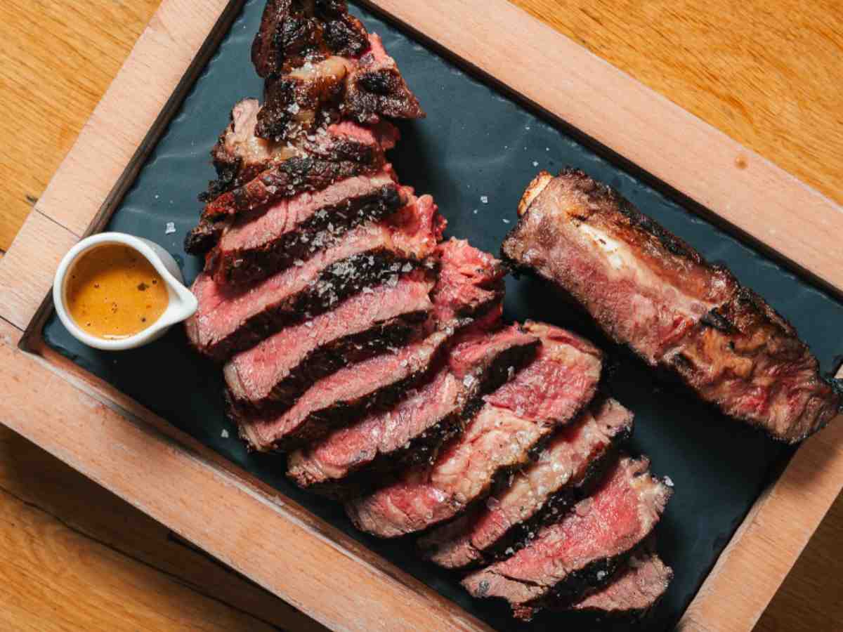 tagliata di carne su un tagliere con accanto una salsina