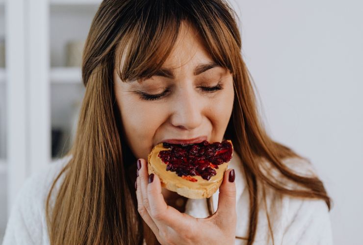 ragazza in primo piano che mangia una fetta di pane e marmellata