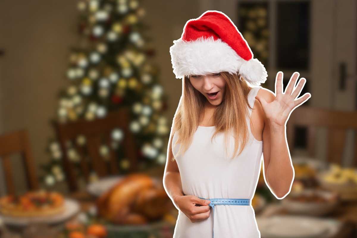 ragazza che si misura i cm in vita con cappello di Natale e sfondo natalizio