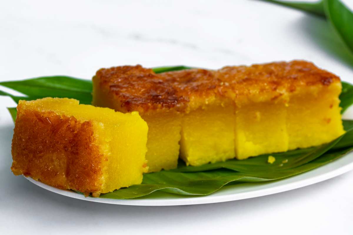 budino al forno di manioca e latte tagliato a quadrati grossi su un vassoio di foglie